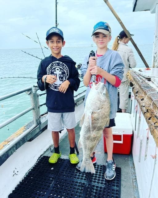 An angler holding a grouper at sunset on the Gulf