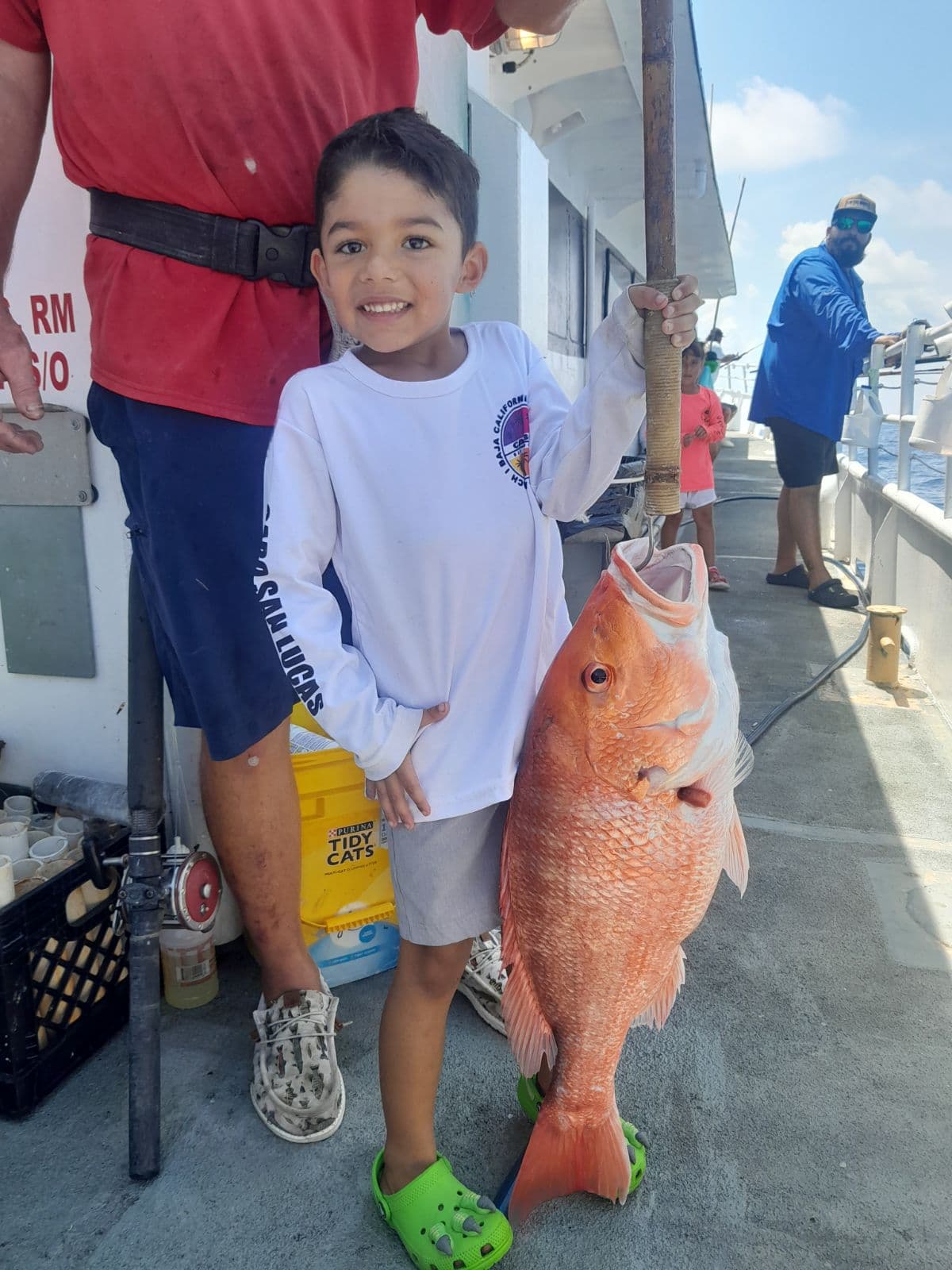 A young angler holding a red snapper on the back deck